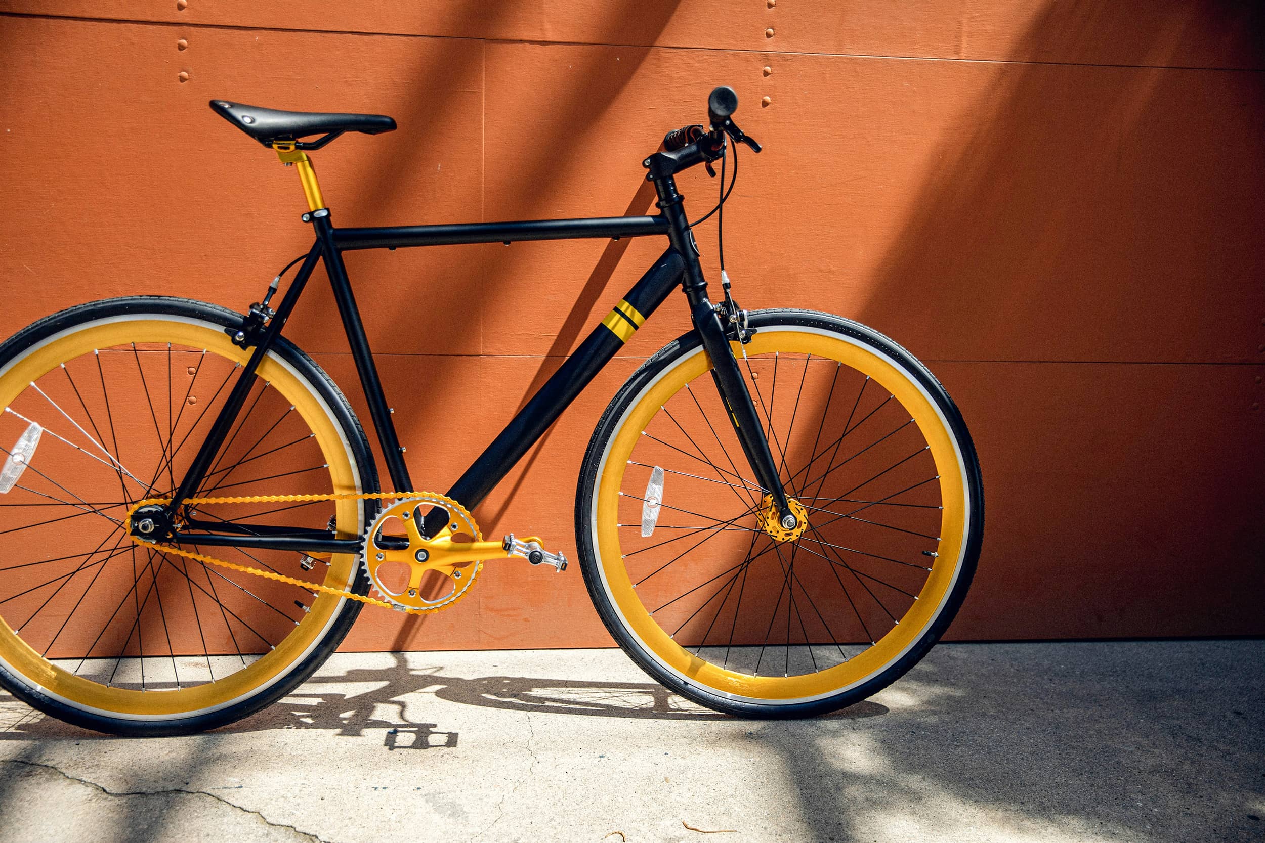 Black bicycle leaning against red wall